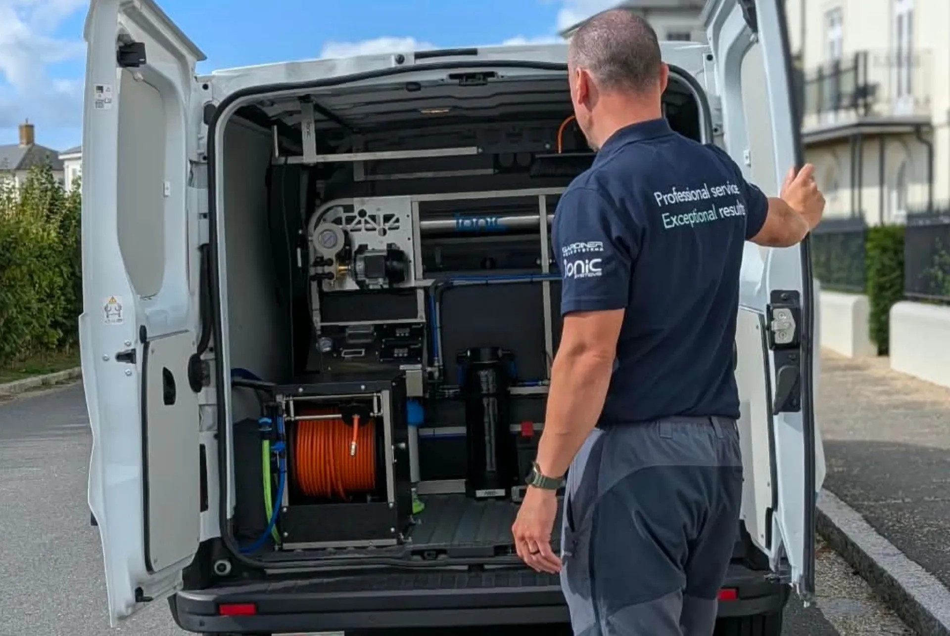 Tom from Mint at the back of the van showing the Ionic pure water filtration system and hose reel