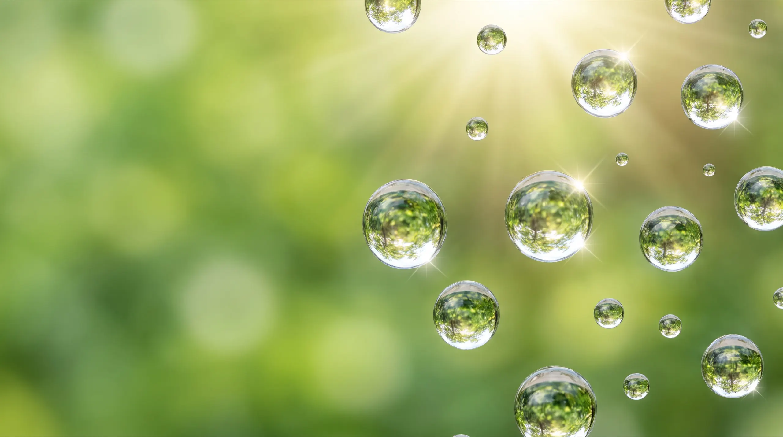 Pure water droplets on clean glass with sunlight and a green garden behind
