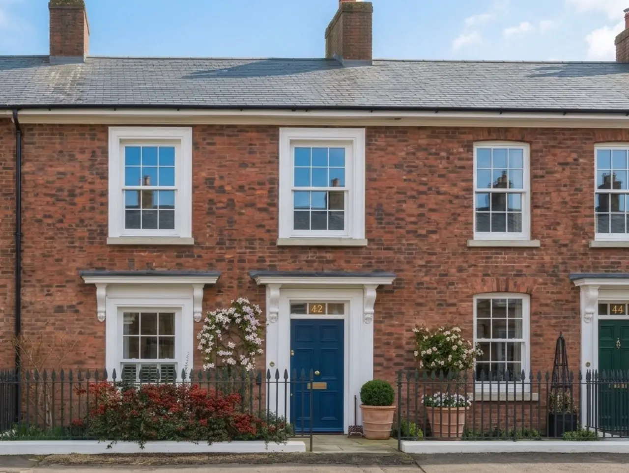 Window cleaning in Poundbury on a red-brick terrace with white sash windows and a blue front door